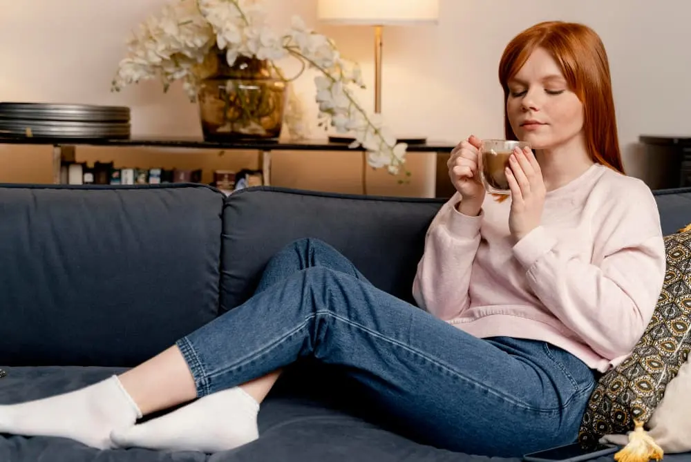 Mujer en sofá con bebida caliente